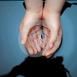 Children`s hands in a dirty liquid, environmental pollution of water by petroleum products