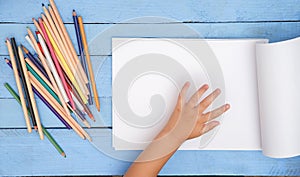 Children`s hands draw with pencils in the album on the blue table