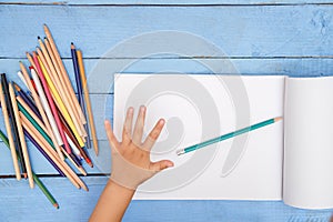 Children`s hands draw with pencils in the album on the blue table