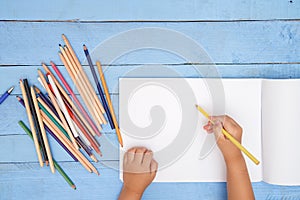 Children`s hands draw with pencils in the album on the blue table