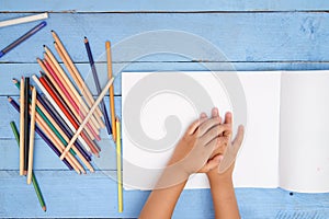 Children`s hands draw with pencils in the album on the blue table