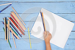 Children`s hands draw with pencils in the album on the blue table