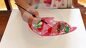 Children's hands draw with watercolours on a sheet, close-up view