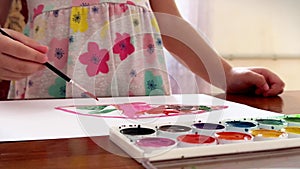 Children's hands draw with watercolours on a sheet, close-up view