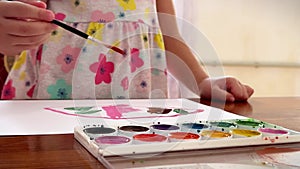 Children's hands draw with watercolours on a sheet, close-up view