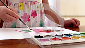 Children's hands draw with watercolours on a sheet, close-up view