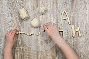 Children`s hands fly figures of salt dough, clay, plasticine on a wooden background. Children`s creativity. Manual