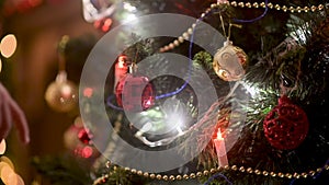 Children`s hands hang a ball decoration on the Christmas tree.