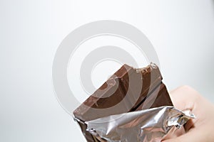 Children& x27;s hands hold a bar of chocolate on a white background.