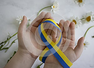 Children`s hands hold a blue-yellow  geopolitics  symbol   ribbon