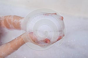 Children`s hands hold the foam. Taking a bath, hygiene procedures