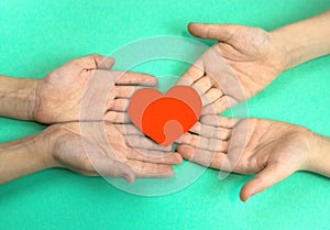 children's hands hold a heart cut out of red paper. Children give love and warmth concept. Peace love in