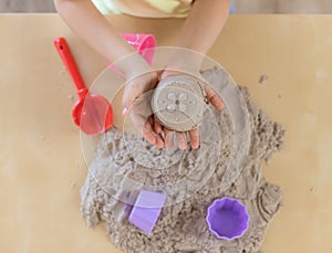 Children`s hands holding a cupcake made of kinetic sand.