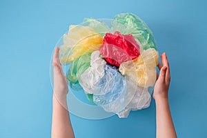 children& x27;s hands holding a set of plastic bags and plastic wraps of different colors on a blue background. top view