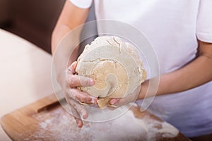 Children`s hands knead the dough on a wooden cutting board. close-up. dough recipe, cooking technology