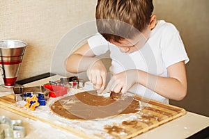 Children`s hands make gingerbread. Small boy cutting cookies for