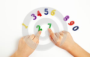 Children& x27;s hands move numbers on a white table. Learning colors and to count from zero to ten