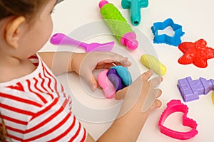 Children`s hands with multicolored plasticine, play dough on white table