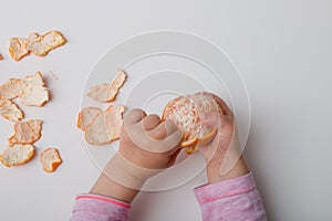 Children`s hands peel orange mamdarin