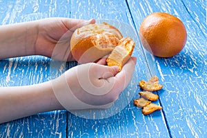 Children's hands peeling tangerine