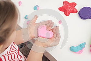 Children`s hands with pink plasticine heart, games with play dough, playdough, mass for modeling, set for creativity, gift for mo