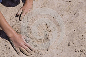 Children`s hands playing in the sand with room to put letters