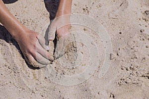 Children`s hands playing in the sand with room to put letters