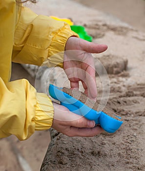 Children's hands playing with sand in a sandbox