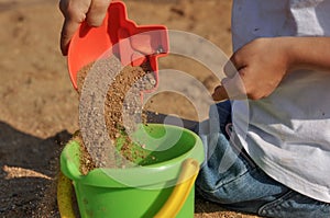 Children's hands playing with sand in a sandbox