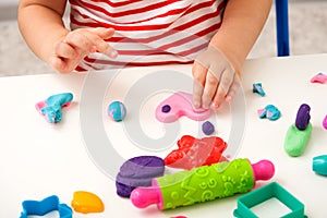 Children`s hands sculpt pink heart from plasticine on white table, children`s educational games, home creativity, play dough, gi