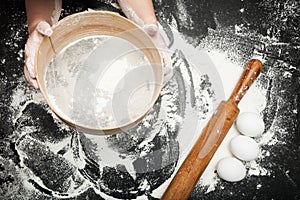 Children`s hands sift the flour on the kitchen table