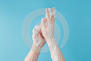 Children`s hands in soap suds, on a blue background, top view