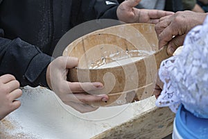 Children`s hands using an old wooden sieve sift flour for making bread.