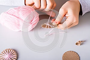 Children`s hands wrap yarn around a cardboard circle for DIY Christmas handmade decorations