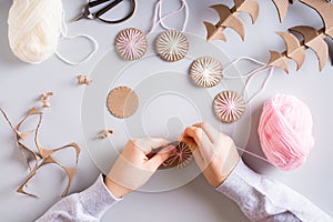 Children`s hands wrap yarn on a cardboard circle for DIY Christmas handmade decorations. Top view
