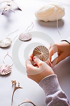 Children`s hands wrap yarn on a cardboard circle for DIY Christmas handmade decorations. Vertical
