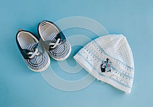 Children`s hat, booties on a blue background. Top view, flat lay