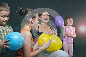 Children`s holiday, mother and children laugh merrily and inflate balloons