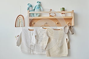 Children`s knitted clothes. Shelf with hanger. Cardigan, sweater, jumper on hanger. Children`s room, nursery