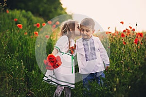 Children`s love, a little boy and a girl, amicably spend time, laugh and smile, and kiss in the flowering field of poppies