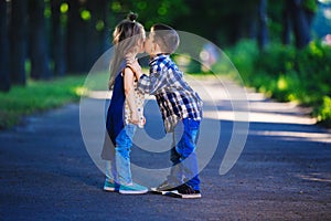 Children`s love, a little boy and a girl, having fun, laugh and smile, and kiss outdoors