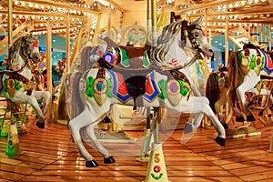 Children`s merry-go-round in an amusement park with colorful horses decorated with glowing light bulbs