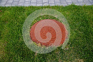 A children`s mound covered with an orange rubberized coating on a green lawn on a clear sunny day. Sports