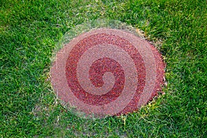 A children`s mound covered with a pink rubberized coating on a green lawn on a clear sunny day. Sports