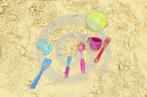 Children`s multi-colored dishes are scattered on the sand