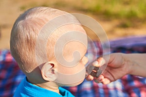 Children`s nape with sparse white hair, close-up. Mom feeds baby pastila