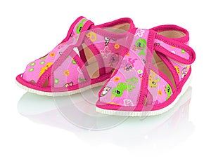 Children`s pink slippers on the white background with shadow reflection.