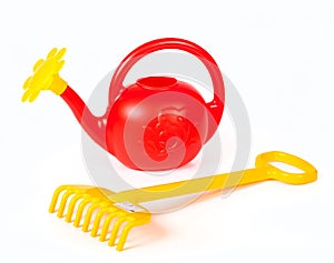 Children`s plastic watering can and yellow rake