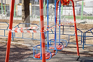 Children`s playground closed and wrapped in alarm caution tape for global coronavirus quarantine.No children on