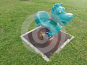 Children`s playground with cyan colored dinosaur spring toy rider